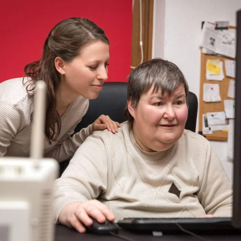 Woman helping friend use a computer