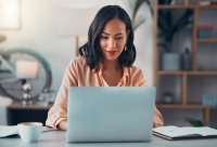 young woman sits at her desk in front of her computer