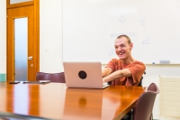 Smiling caucsian man with cerebral palsy working using laptop in a meeting room in a coworking