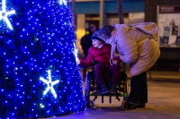 Heartwarming scene of a disabled child in a wheelchair, sharing a moment of joy with their mother near a brightly lit christmas tree